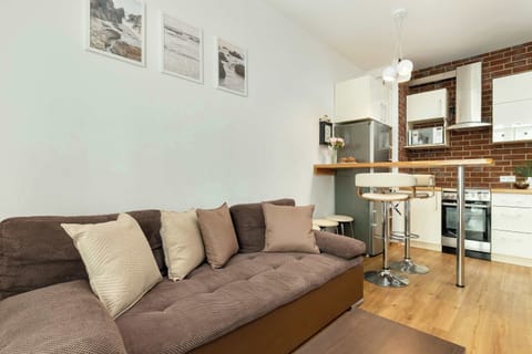 A living room area with a brown sectional sofa, wall art, and a small bar table connected to the kitchenette.