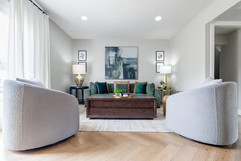 Newly renovated open living room with herringbone hardwood floors, vaulted ceilings, designer furnishings, and smart TV. Designed for groups of 12 gathering before or after the game.