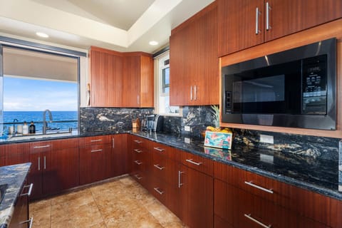 Rich koa-tone cabinetry, five-burner cooktop, and granite counters make prepping poke bowls a pleasure—plus the sea is always in sight.