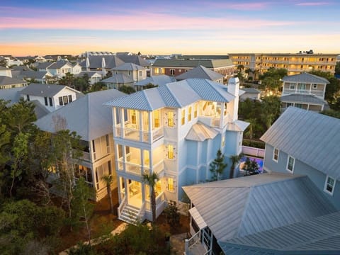 Beautiful coastal home captured at sunset with warm interior lighting, highlighting classic architecture and inviting outdoor spaces.