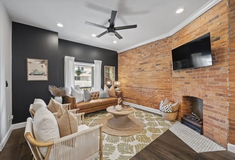 Relax in the cozy living room with exposed brick walls and stylish decor   - Comfortable seating and smart TV create the perfect gathering spot   - Natural light fills this inviting modern space
