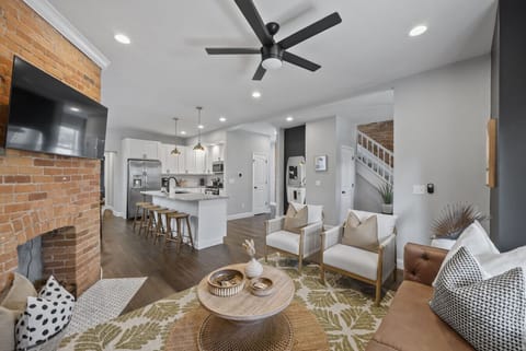 Cozy up on the sofa with warm tones and chic pillows in a welcoming space   - Enjoy views of the modern kitchen and dining area from the living room   - Perfect setup for family time or entertaining friends with open floor plan