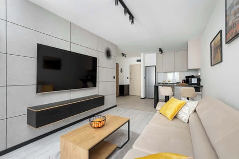 Wall-mounted TV with a stylish white and yellow sofa underneath.