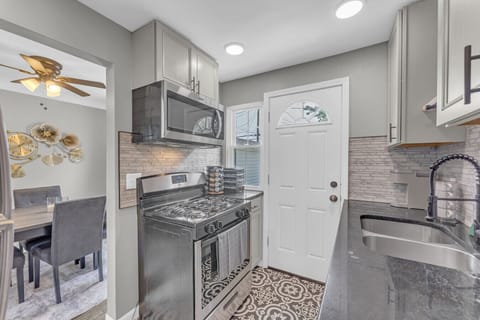 Fully equipped kitchen with stainless steel stove   - Modern backsplash and stylish patterned flooring   - Easy access to dining area for home cooked meals