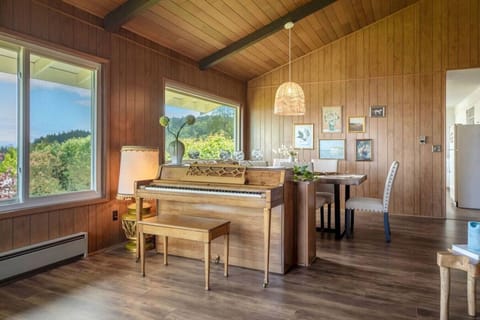 Bright dining space with a charming piano and large windows that fill the room with natural light and serene views 🎹✨