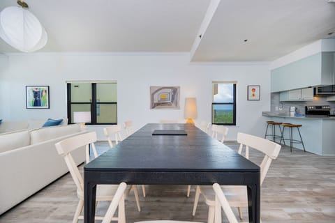 Bright and airy dining area featuring a sleek black table, modern decor, and inviting views through large windows
