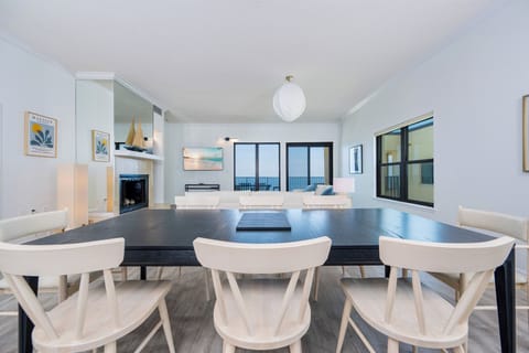 Open dining area with a large black table, stylish chairs, and panoramic views through expansive windows