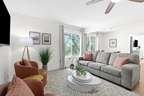 Spacious seating area with plush sofa, modern armchairs, and large windows for natural light.