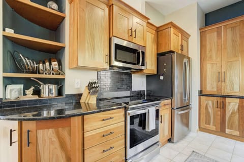Fully equipped kitchen with stainless steel appliances, rich wood cabinetry, and dark countertops, perfect for preparing meals with ease.