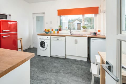 Red fridge/freezer, washing machine and dishwasher. Door leading to the rear garden