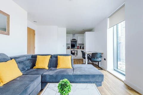 A cozy living room with a plush sofa flows seamlessly into a modern, fully equipped kitchen, creating the perfect space for relaxing and dining in one.