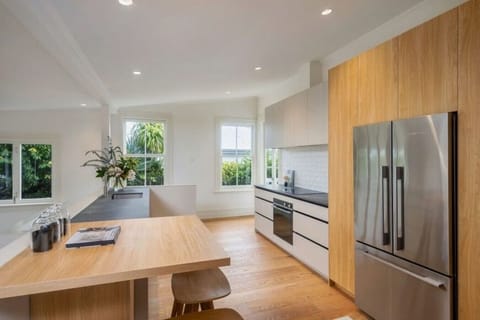 Modern fully equipped kitchen, elevated above the open plan living space, with bar seating, large fridge freezer, oven, stovetop, microwave, waste disposal, Nespresso machine, kettle and toaster