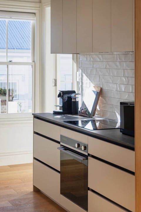 Modern fully equipped kitchen, elevated above the open plan living space, with bar seating, large fridge freezer, oven, stovetop, microwave, waste disposal, Nespresso machine, kettle and toaster