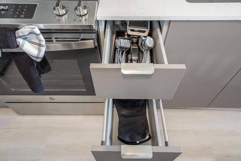 Fully stocked modern kitchen with utensils, cookware, and tableware.