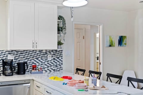 Kitchen counter with coffee maker, kettle, and colorful kids' dishes.