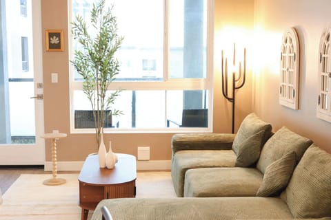 Spacious living room featuring a cozy L-shaped sofa, a full-size air mattress, and a 65" Smart TV with preloaded access to Netflix, Hulu, and Disney+, all set up for your enjoyment.