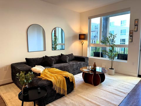 Spacious living room featuring a cozy L-shaped sofa, a full-size air mattress, and a 65" Smart TV with preloaded access to Netflix, Hulu, and Disney+, all set up for your enjoyment.