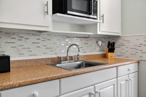 Bright and functional kitchen with sink, microwave, toaster, and knife set.