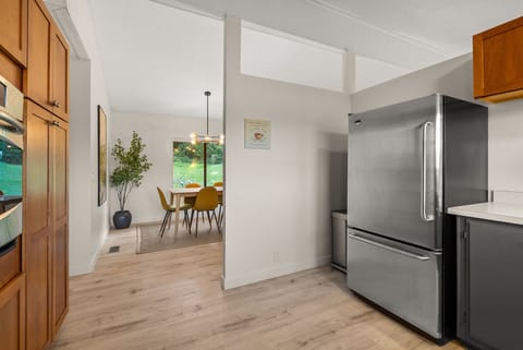 Modern kitchen featuring a large stainless fridge, built-in wall oven, and a dining area just beyond—ready for gatherings and good times