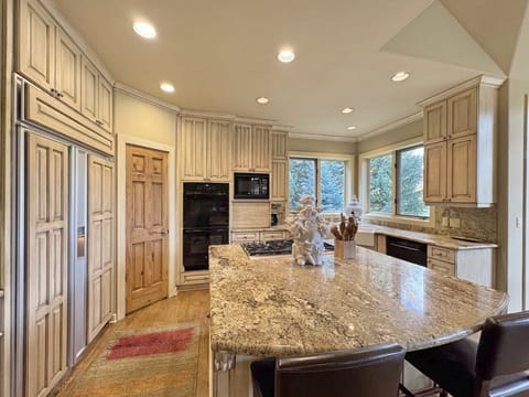This view of the kitchen showcases the dual ovens, refrigerator, freezer and kitchen island