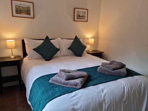 Bedroom with king sized bed, wall mounted TV and built in wardrobe