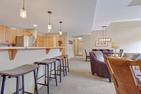 Spacious kitchen with stainless steel appliances and a long breakfast bar with seating for four, flowing into a comfortable dining area and cozy living space. Perfect for entertaining after a day on the slopes.