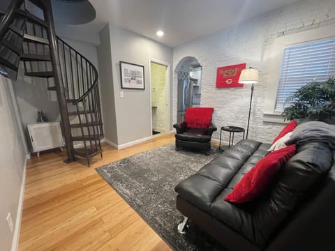 Living room with queen futon couch, half bath and spiral staircase.