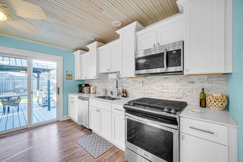 Fully stocked modern kitchen with stainless steel appliances, stone countertops, breakfast bar, and Keurig - everything you need for a beach getaway.
