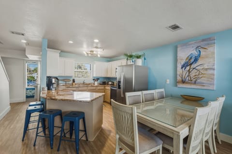 Dining table seats 7, with 4 barstools at counter and ample living room seating.