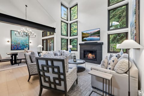 The stunning living room with vaulted ceilings, floor to ceiling windows, and cozy gas fireplace