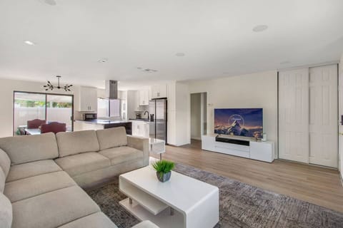 Open-concept living room with high ceilings, comfy seating, gas fireplace, Smart TV, and side yard access.