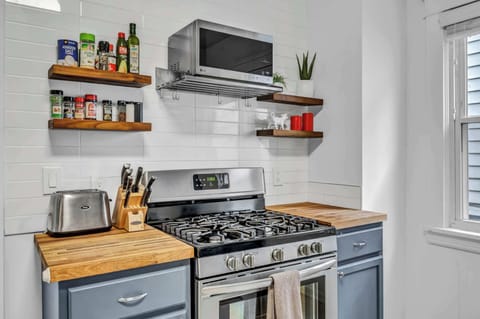 Charming home kitchen with stainless appliances, wood accents, and open shelves — perfect for morning coffee or cooking together.