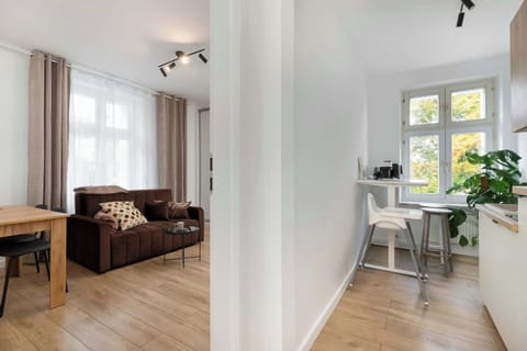 A larger bedroom with a double bed, bedside tables, and windows allowing sunlight to brighten the room. The décor is modern and simple.