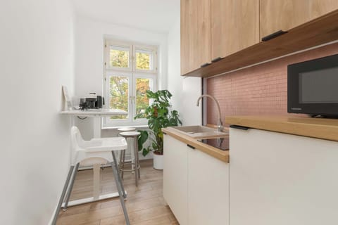 Kitchen area with white cabinets, wooden countertops, and a small dining bar. Two stools are placed by the window, creating a cozy breakfast spot.