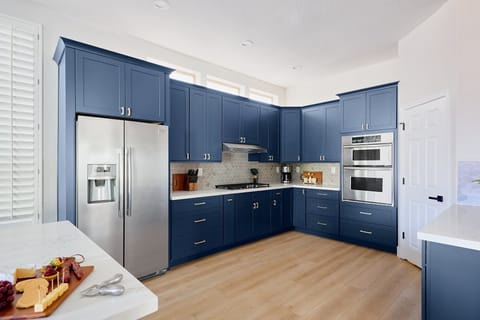 Stylish and functional kitchen with stainless steel appliances, navy cabinetry, marble countertops, and a spacious island with breakfast bar seating for 4.