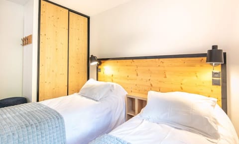 The cozy twin bedroom features warm wooden accents and soft bedding, ensuring a restful night's sleep.