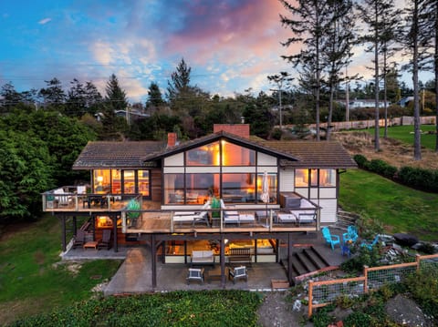 Sunset view of the main house with glowing interior lights and deck seating.