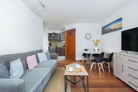 A cozy kitchen with wooden cabinets and beige tiles. Stainless-steel appliances and a small dining table make it both practical and inviting.