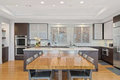 With premium appliances and ample cabinetry, the kitchen is both practical and stylish. At the center is a wood-finish 6-seater dining table, a spacious kitchen island, and a delicate orchid add the perfect touch to the open design.