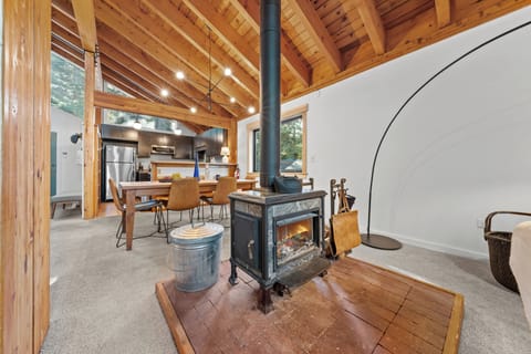 Open-concept living and dining space with exposed beams and a fireplace.