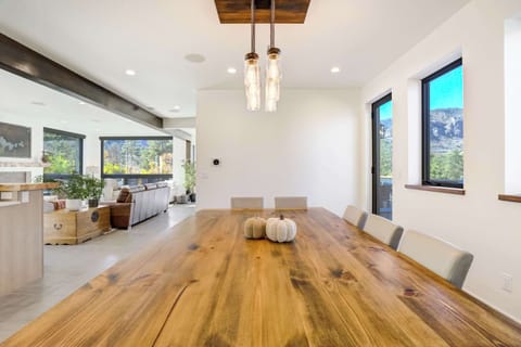 A spacious dining table sits beneath elegant lighting, creating the perfect setting for family meals or relaxed evenings surrounded by scenic Colorado beauty.