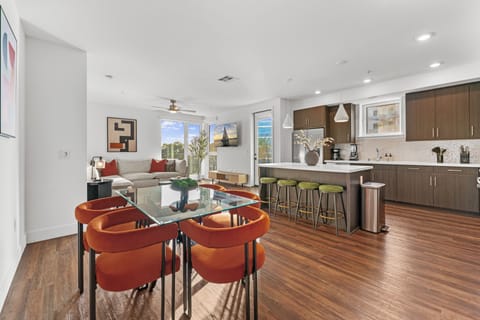 Dine in style at the glass-top table featuring six vibrant orange chairs 