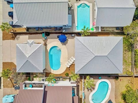 Private backyard oasis with a heated pool, plenty of lounge chairs, outdoor dining, gas grill, and a covered porch with comfy seating—perfect for family cookouts, poolside relaxation, and unwinding after a fun day at the Destin beach.