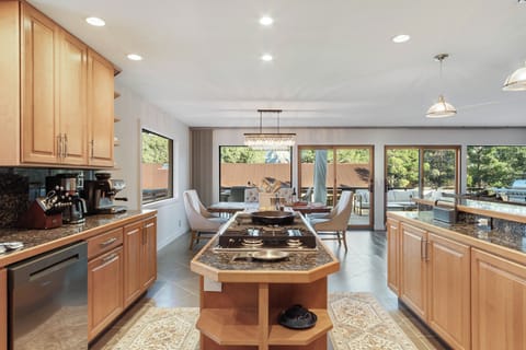 A gourmet kitchen featuring modern appliances, espresso machine with accessories, cast iron cookware, chef-style spice display, breakfast nook seating for four, and picturesque mountain views from the kitchen sink.