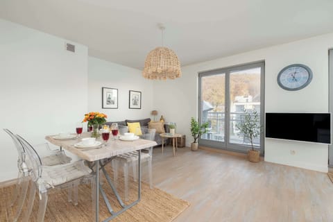 An elegant dining room with a simple table, natural lighting and a woven pendant lamp.