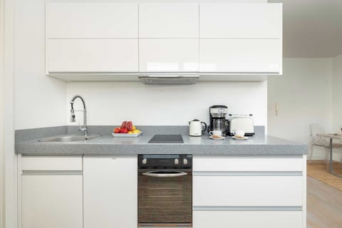 A compact modern kitchen with white cabinets and built-in appliances.