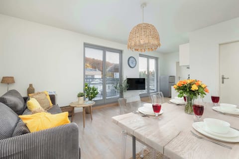 A spacious living room with a sofa, rug, and large windows bringing in daylight.