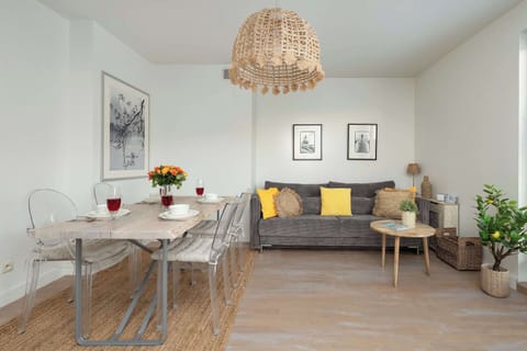 A bright living and dining area with light wooden floors, table, and wall art creating a cozy atmosphere.