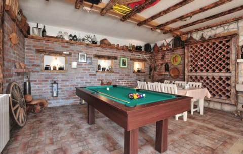 The billiard room (34 sqm) provides indoor entertainment with a pool table, an extra dining table, and a rustic decor featuring a large wine rack.
