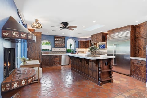 Fully equipped kitchen with stainless steel appliances, a sleek kitchen island, ample counter space, and a gas fireplace.